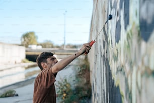 Un uomo che dipinge un muro con un rullo di vernice