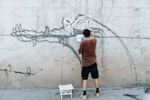 Un uomo in piedi davanti a un muro con graffiti su di esso
