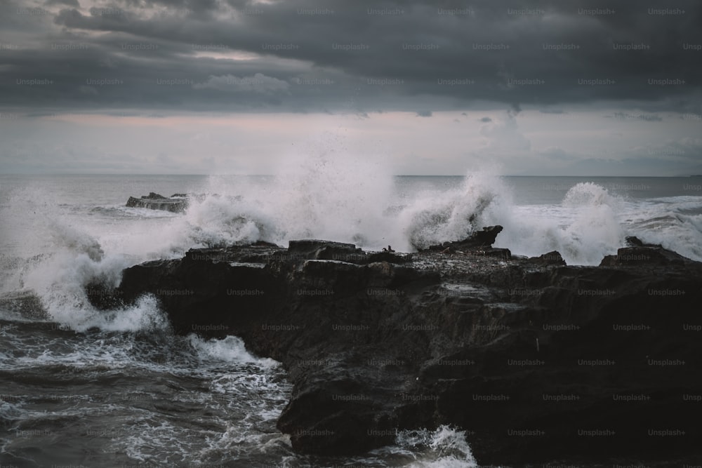 uma grande onda cai contra uma costa rochosa