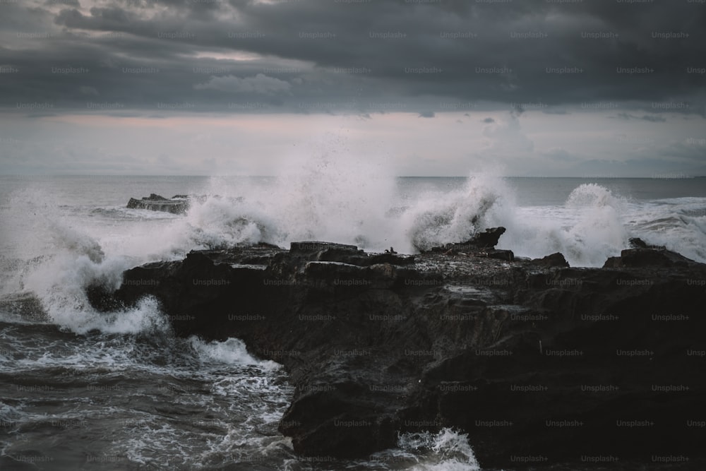 a large wave crashes against a rocky shore