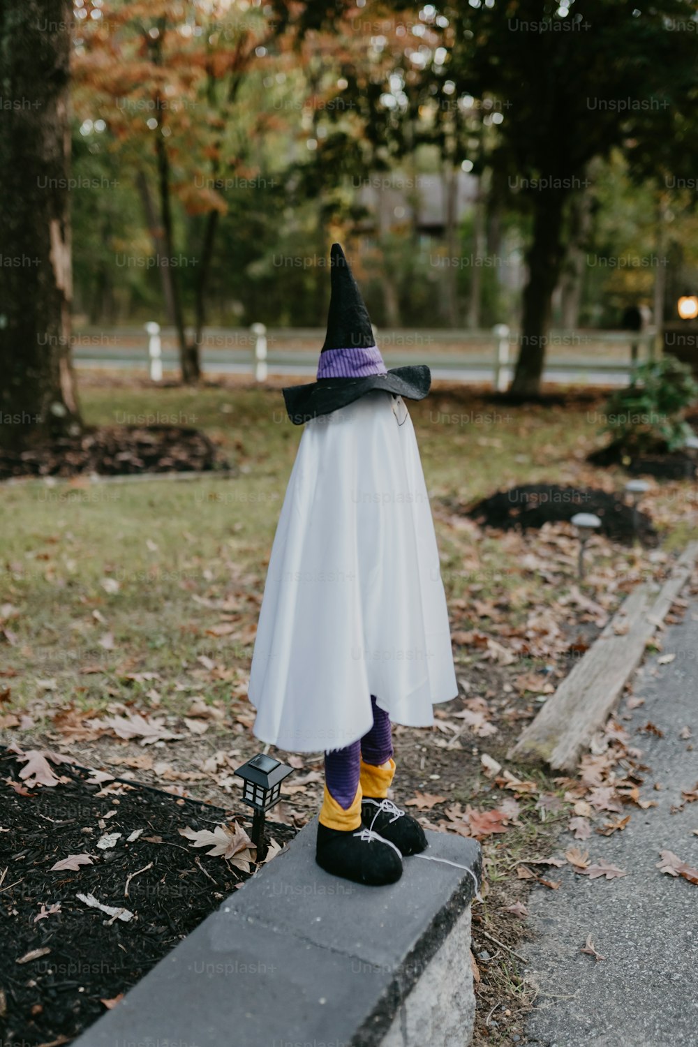 a little girl dressed in a white dress and a witch hat