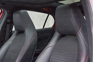 the interior of a car with black leather and red stitching