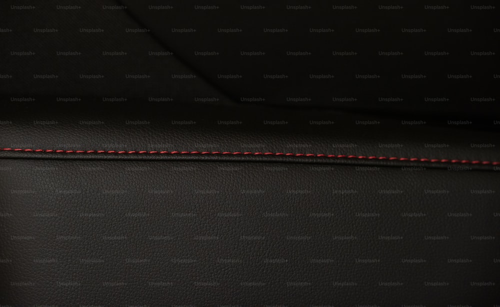 um close up de um assento de couro preto com costura vermelha