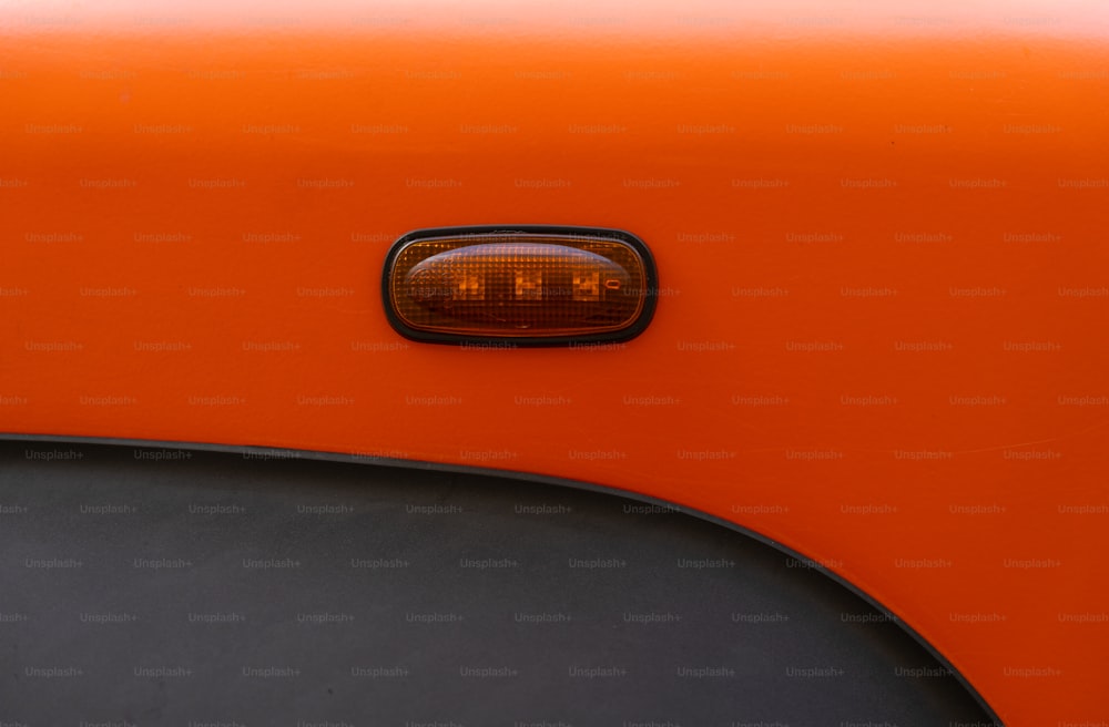 a close up of an orange car with a light on