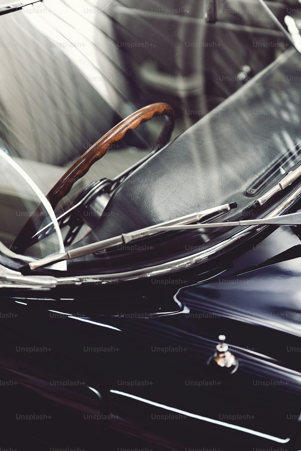 a close up of a black car with a wooden steering wheel