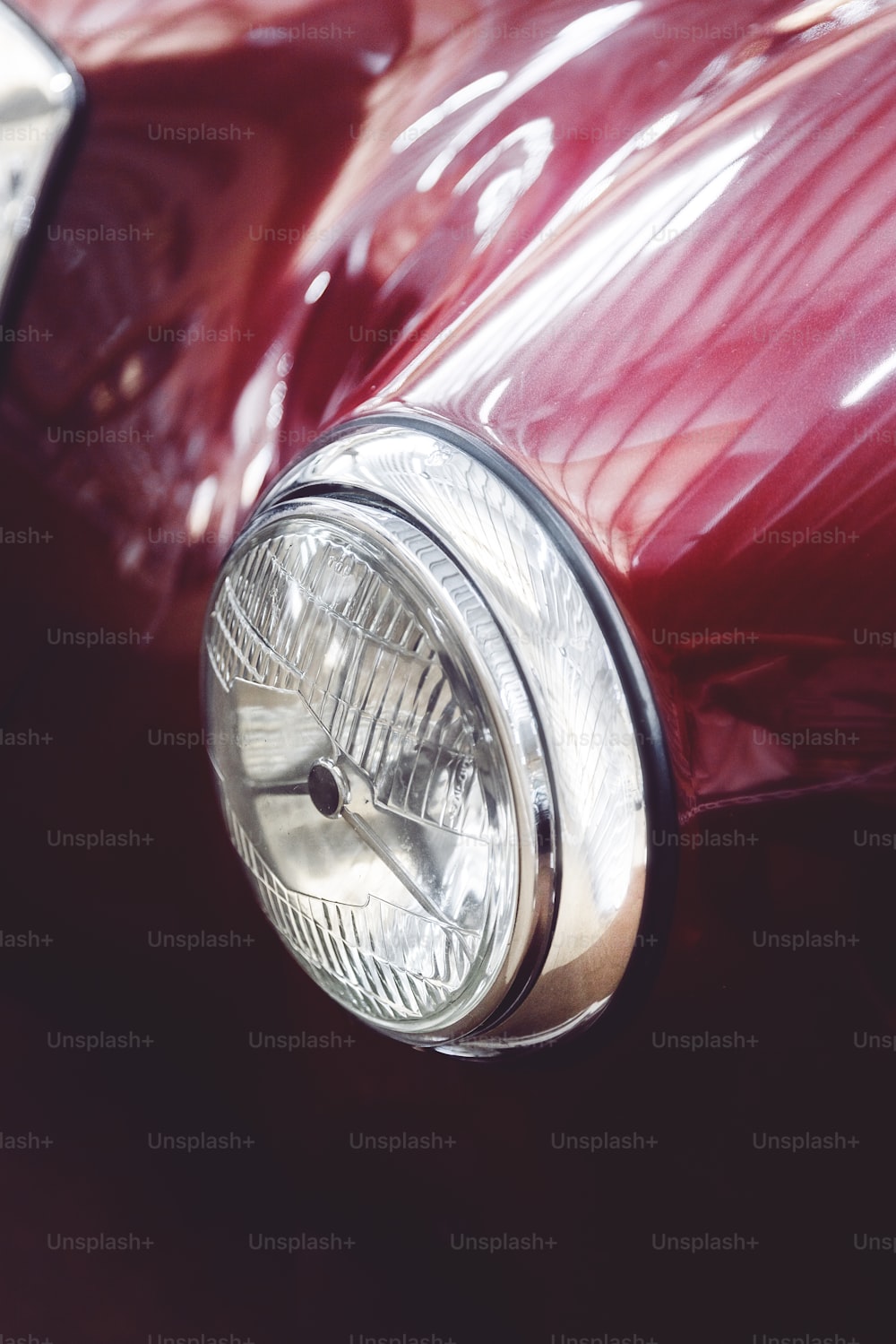 a close up of a shiny red car headlight
