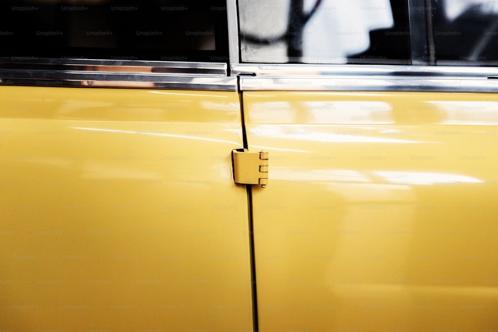 배경에 사람이 있는 노란색 자동차 문을 클로즈업합니다