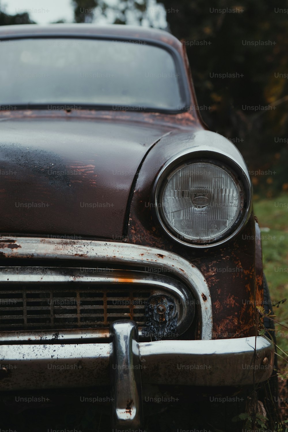 an old rusted out car sitting in a field