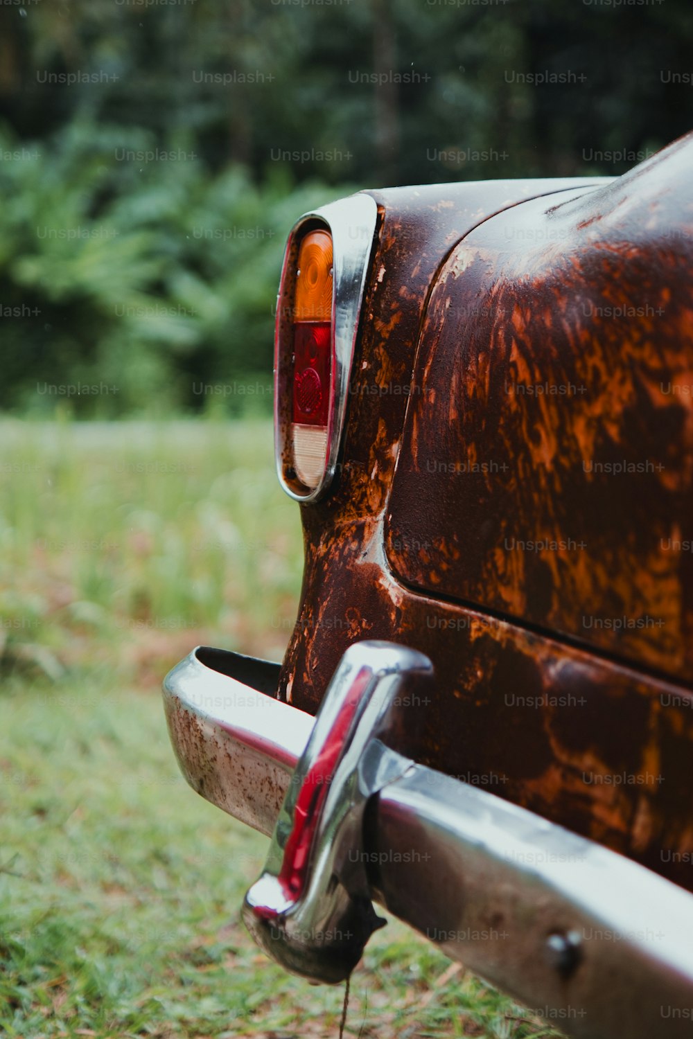 a rusted old car parked in a field