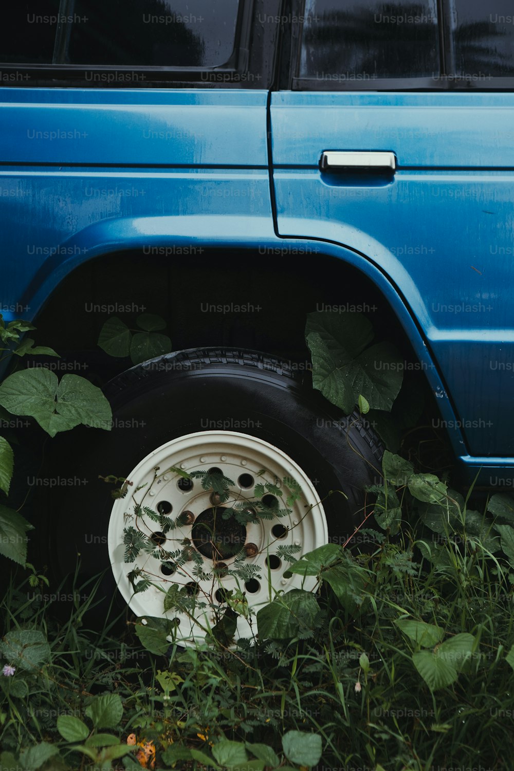 a blue van parked in the grass with a tire