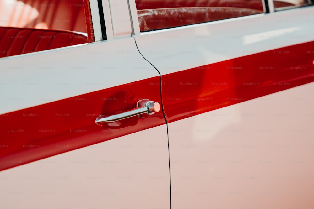 Un primer plano de la manija roja y blanca de la puerta de un automóvil