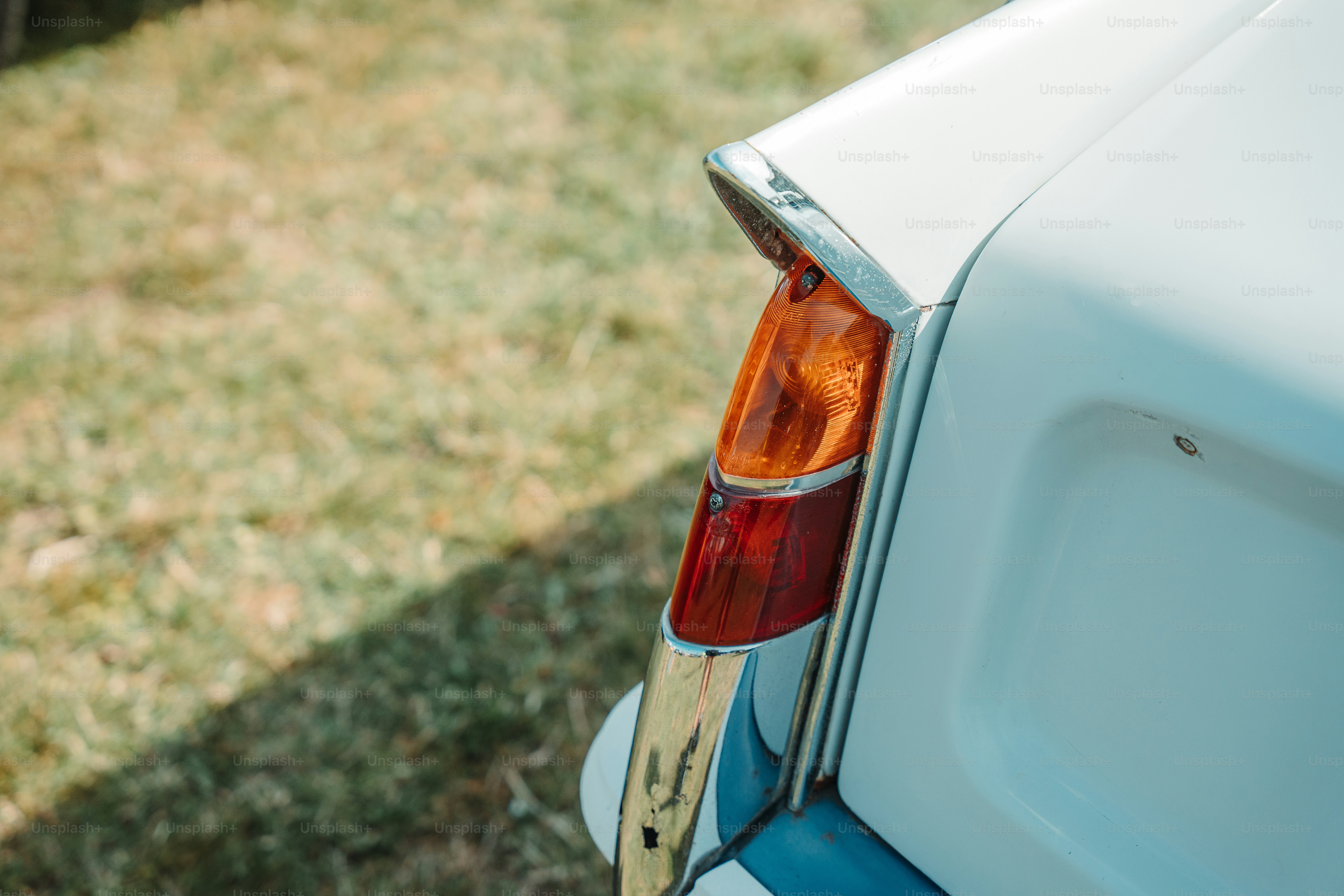 the tail light of a white car with a wooden stick sticking out of it