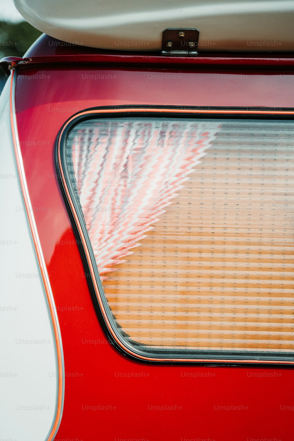 a close up of a red car with a surfboard on top of it