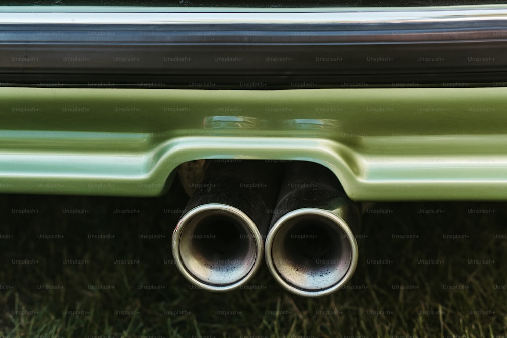 a close up of a green car with two exhaust pipes