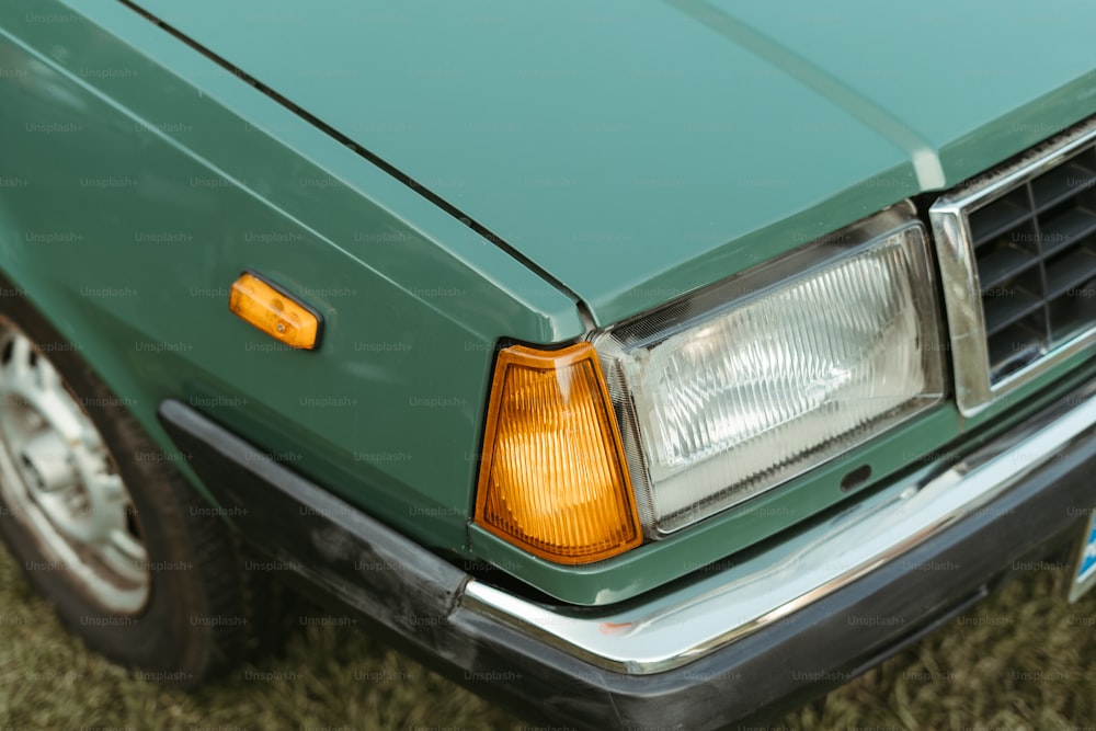 a close up of a green car parked on a grass covered field