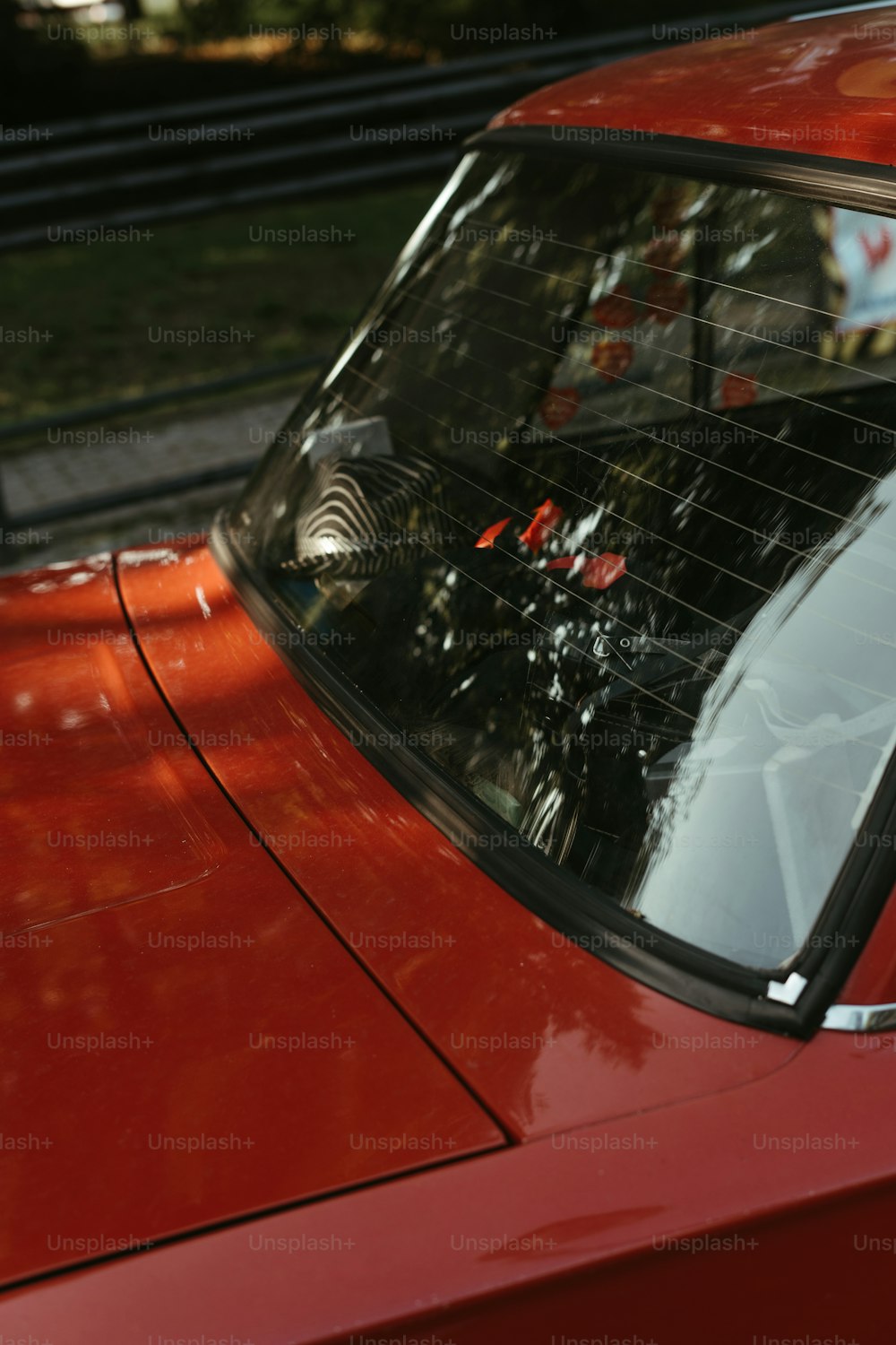 a close up of a red car with a bird on it's windshield