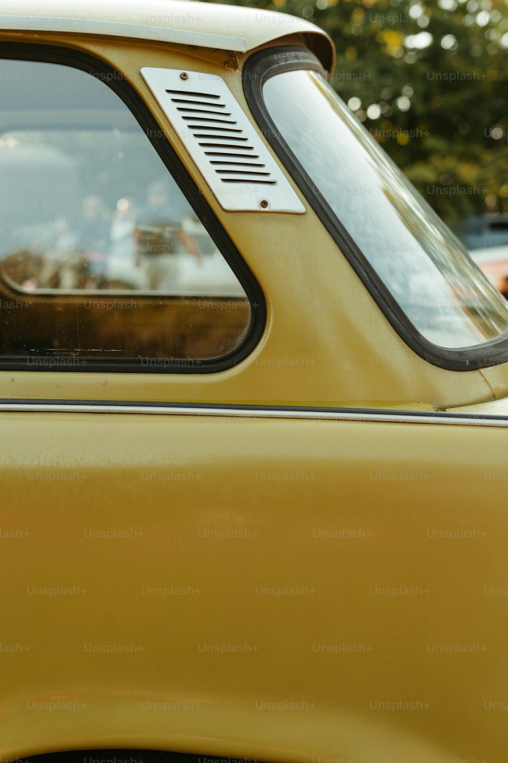 a close up of a yellow car with a dog sticking its head out the window