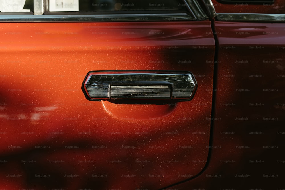 a close up of a door handle on a red car