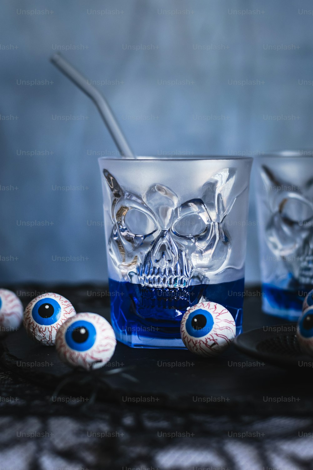 a glass filled with blue liquid and two evil eyeballs