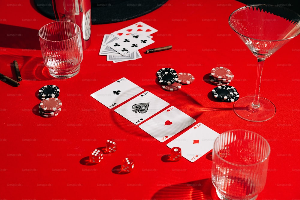 Una mesa roja cubierta con tarjetas y copas de vino