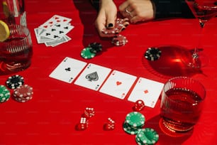 a red table topped with cards and glasses of wine