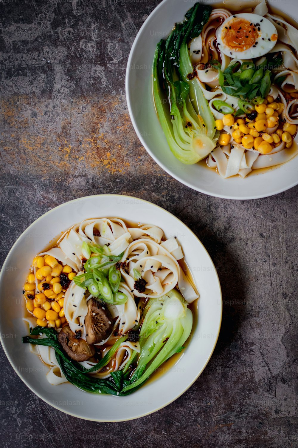 two bowls of noodles and vegetables on a table