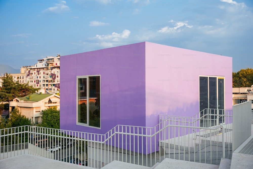 un bâtiment rose et violet avec des escaliers qui y mènent