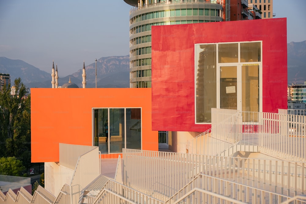 a red and orange building next to a white fence