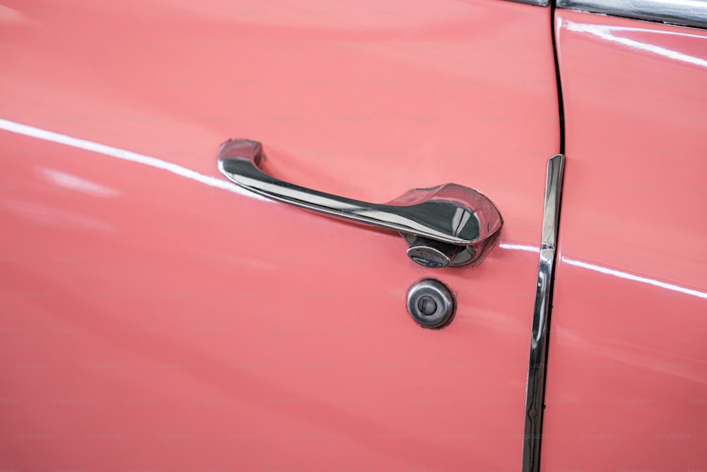Un primer plano de la manija de una puerta en un coche rosa