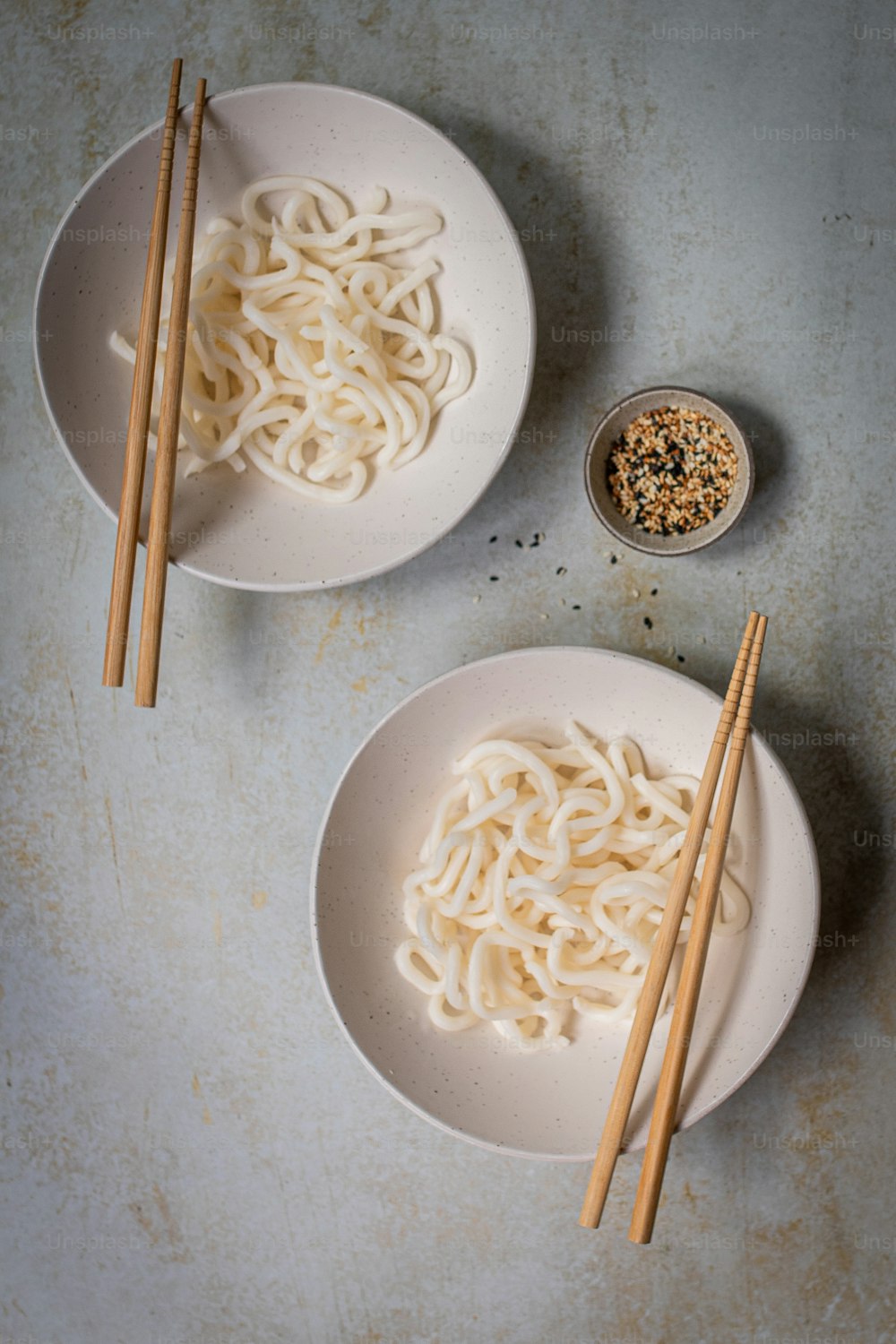 two bowls of noodles with chopsticks on a table
