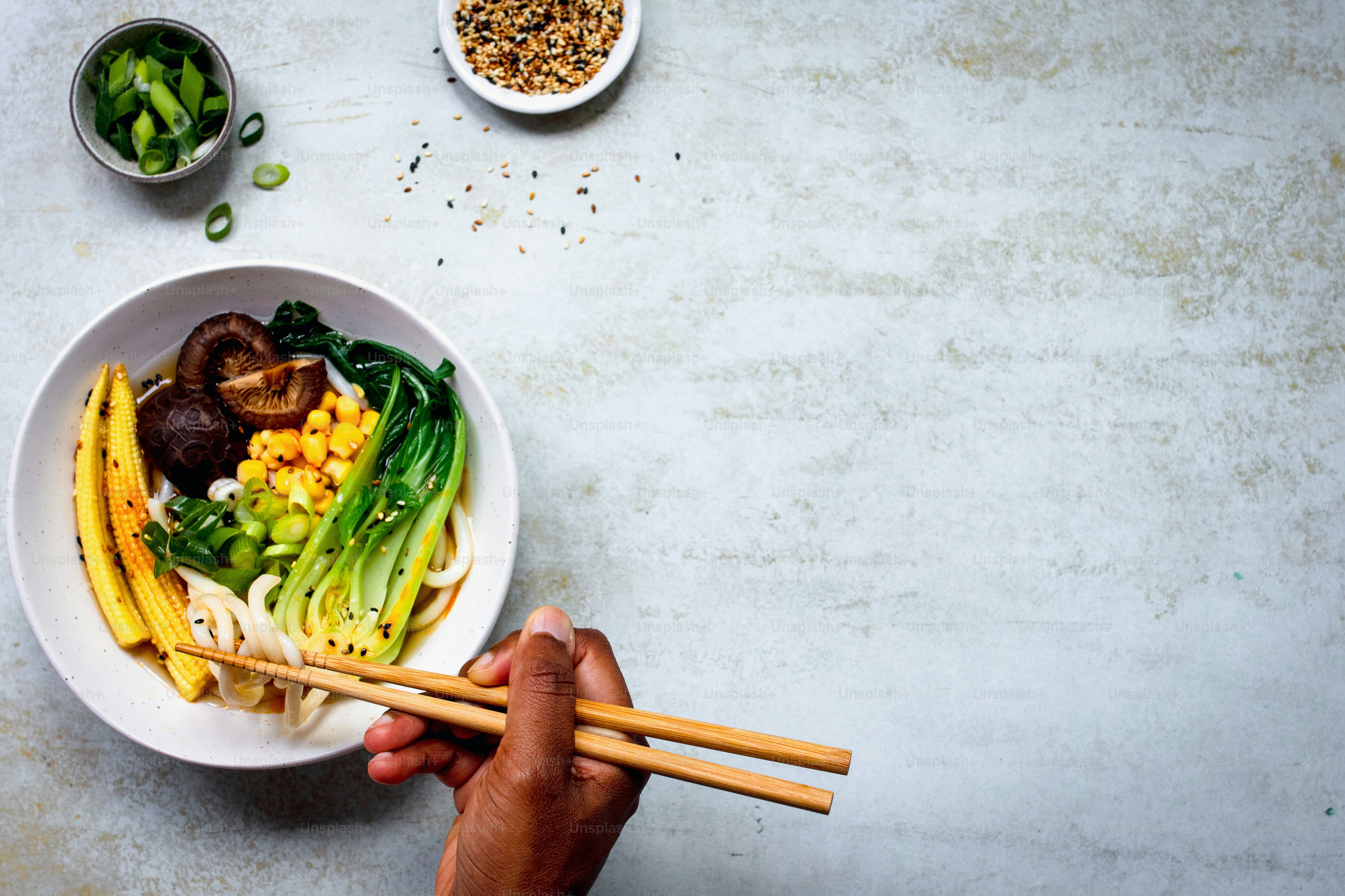 Una persona sosteniendo palillos sobre un tazón de comida