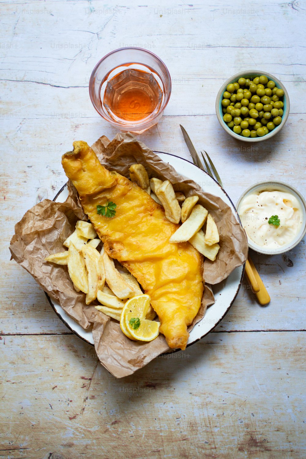 um prato de peixe e batatas fritas com um lado de ervilhas