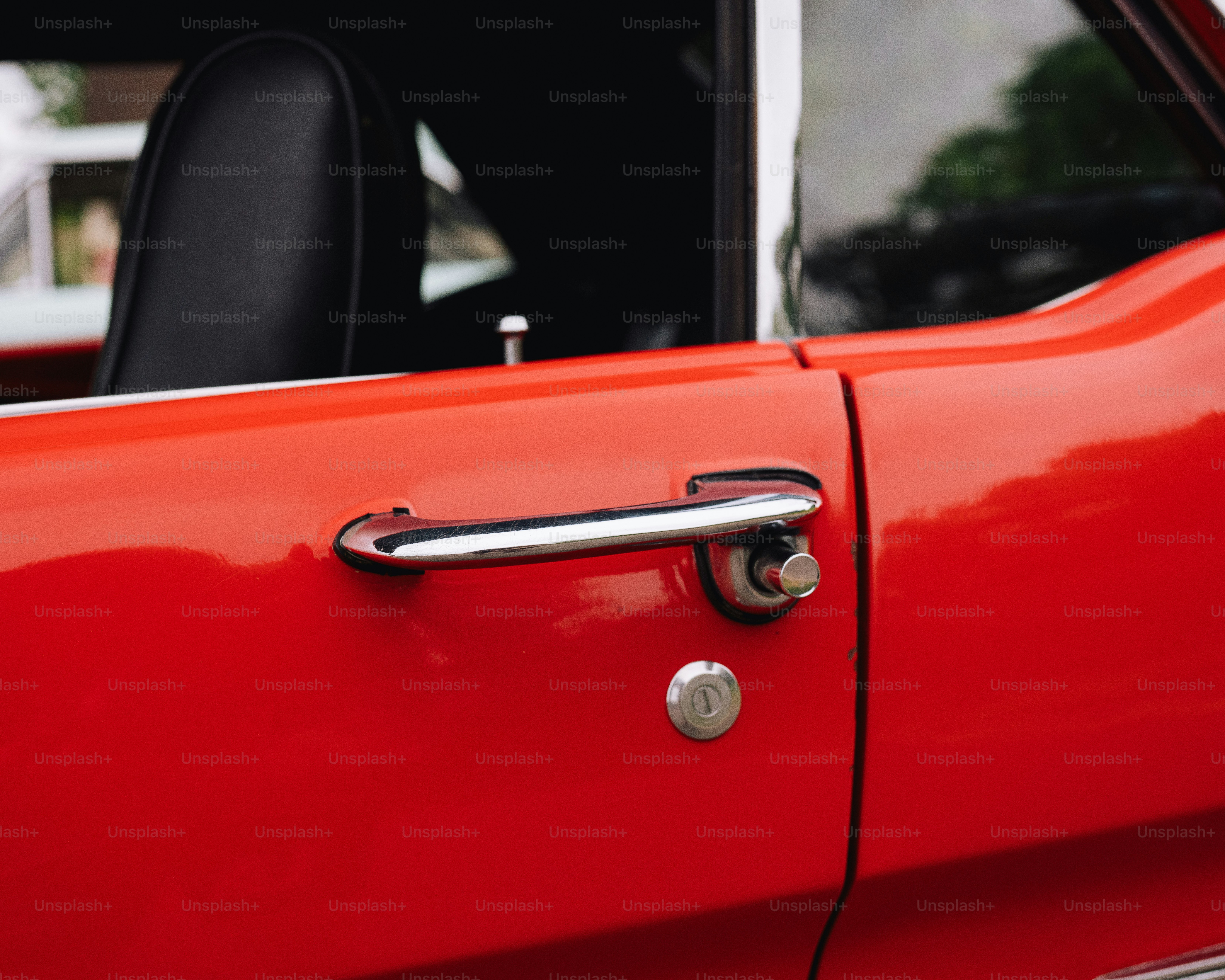 Gros plan d’une poignée de porte sur une voiture rouge