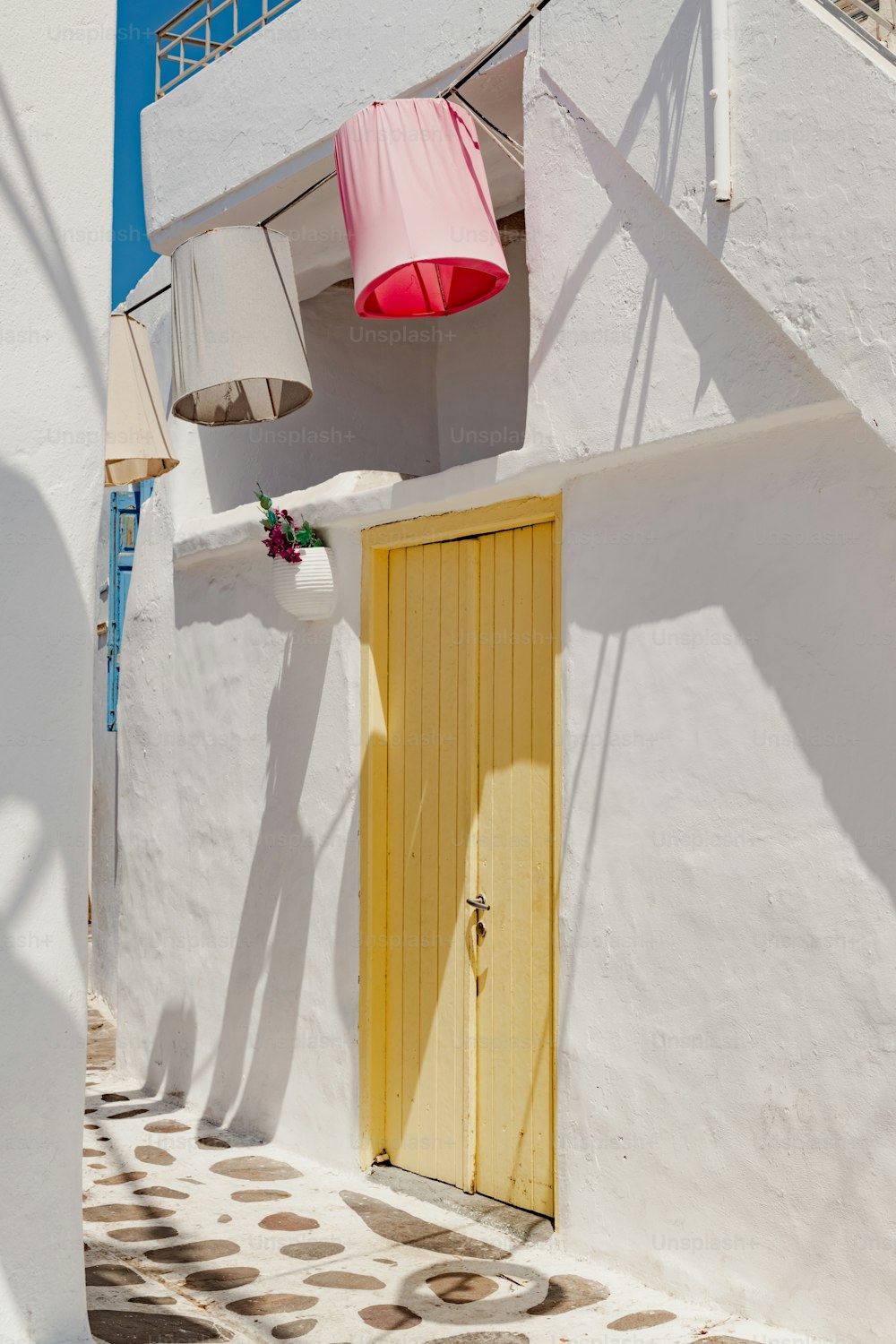 a white building with a yellow door and a pink lamp