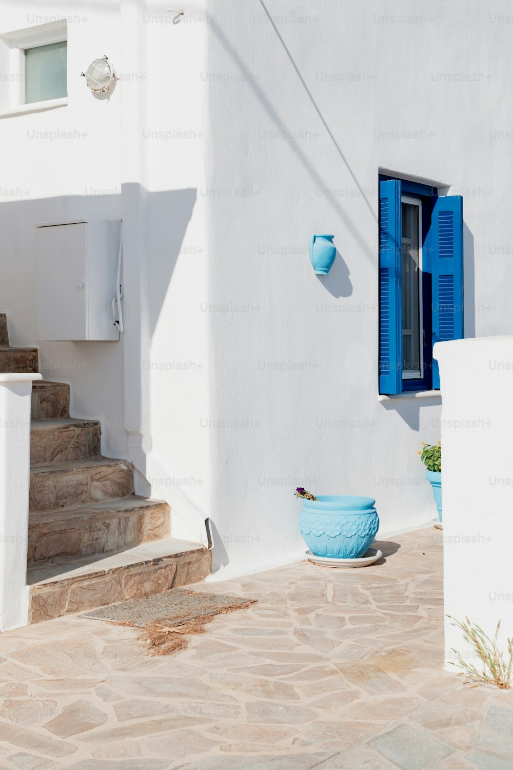 Ein weißes Haus mit blauen Fensterläden und einer blauen Schale