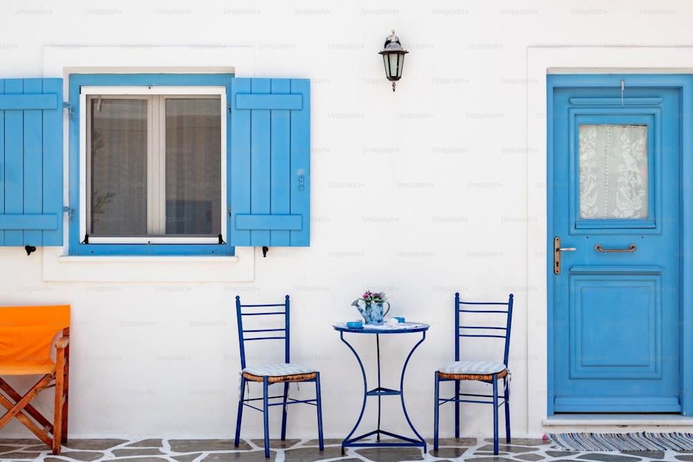 two chairs and a table in front of a blue door