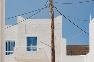 a white building with blue shutters and a wooden pole