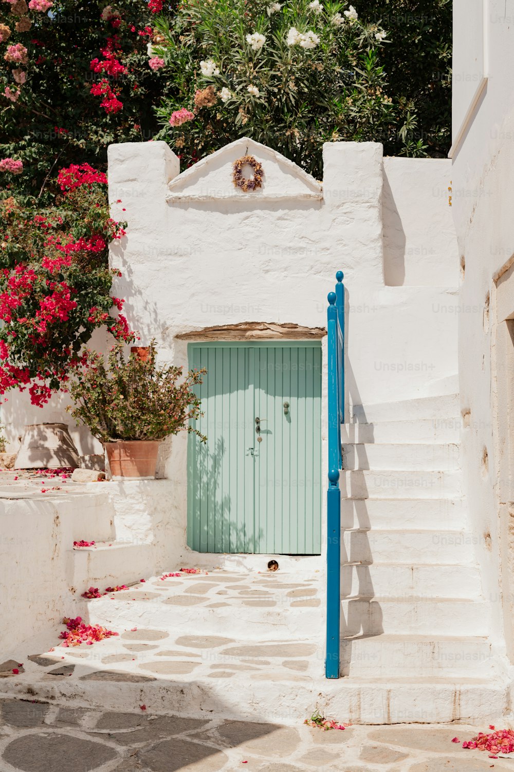um edifício branco com uma porta azul e escadas