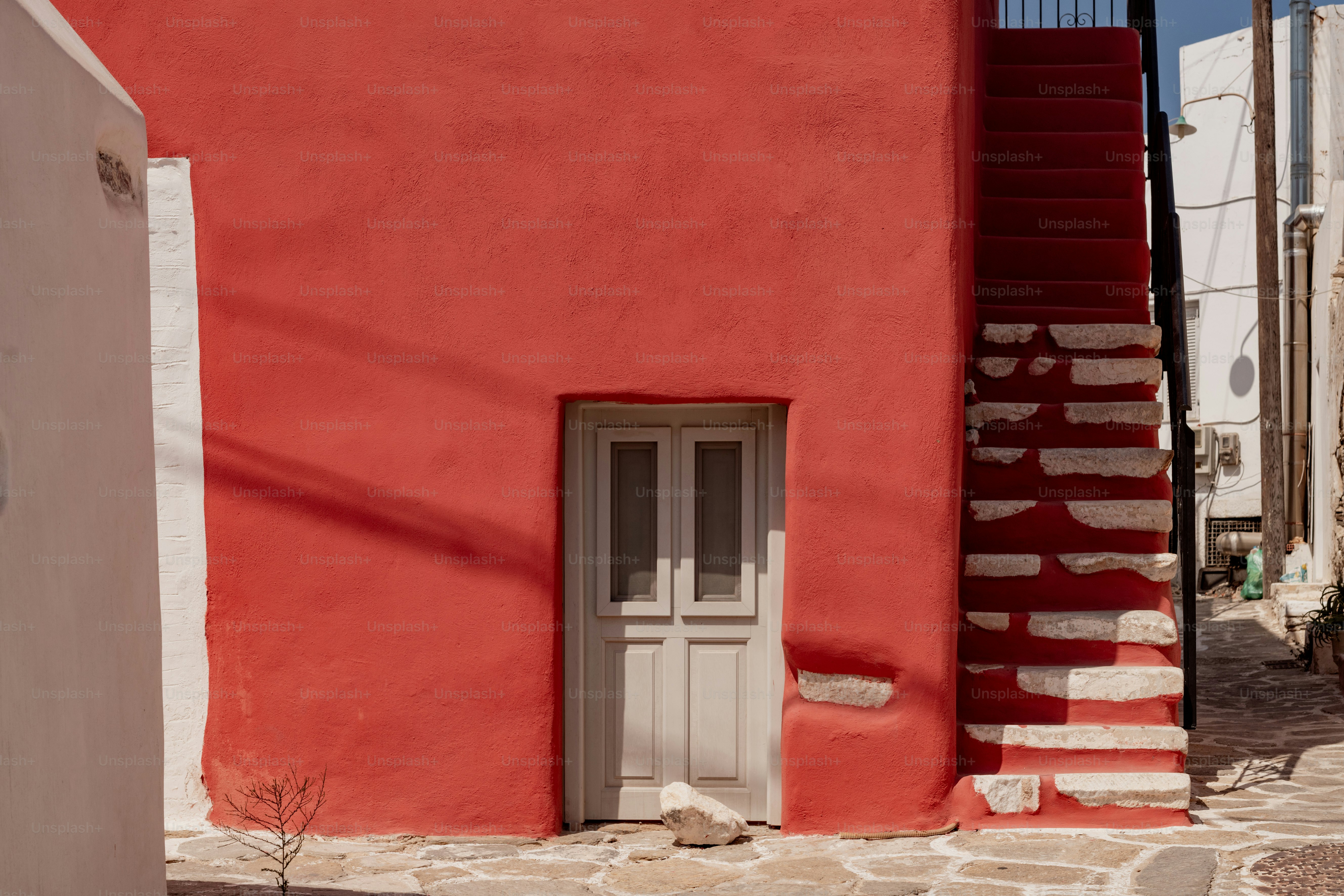 um edifício vermelho com uma porta branca e uma escada