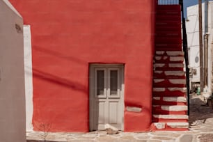 a red building with a white door and a stair case