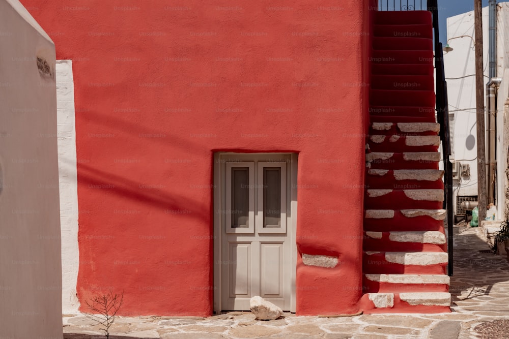 a red building with a white door and a stair case