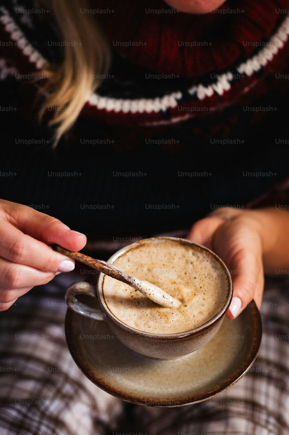a woman holding a cup of coffee with a spoon in it