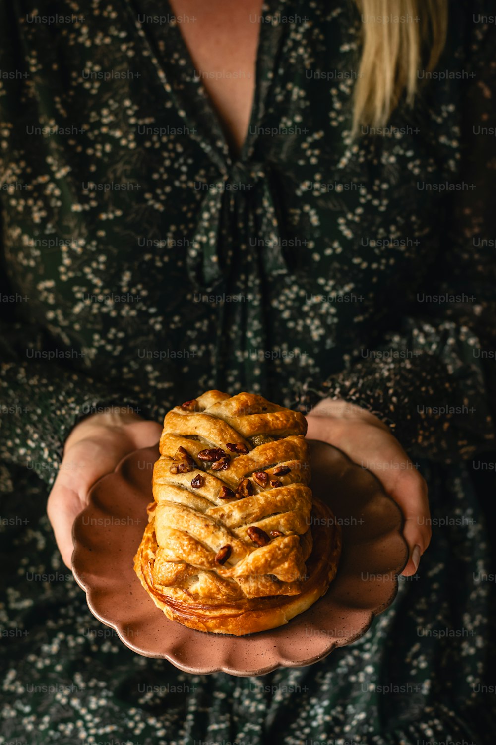 a person holding a plate with a pastry on it