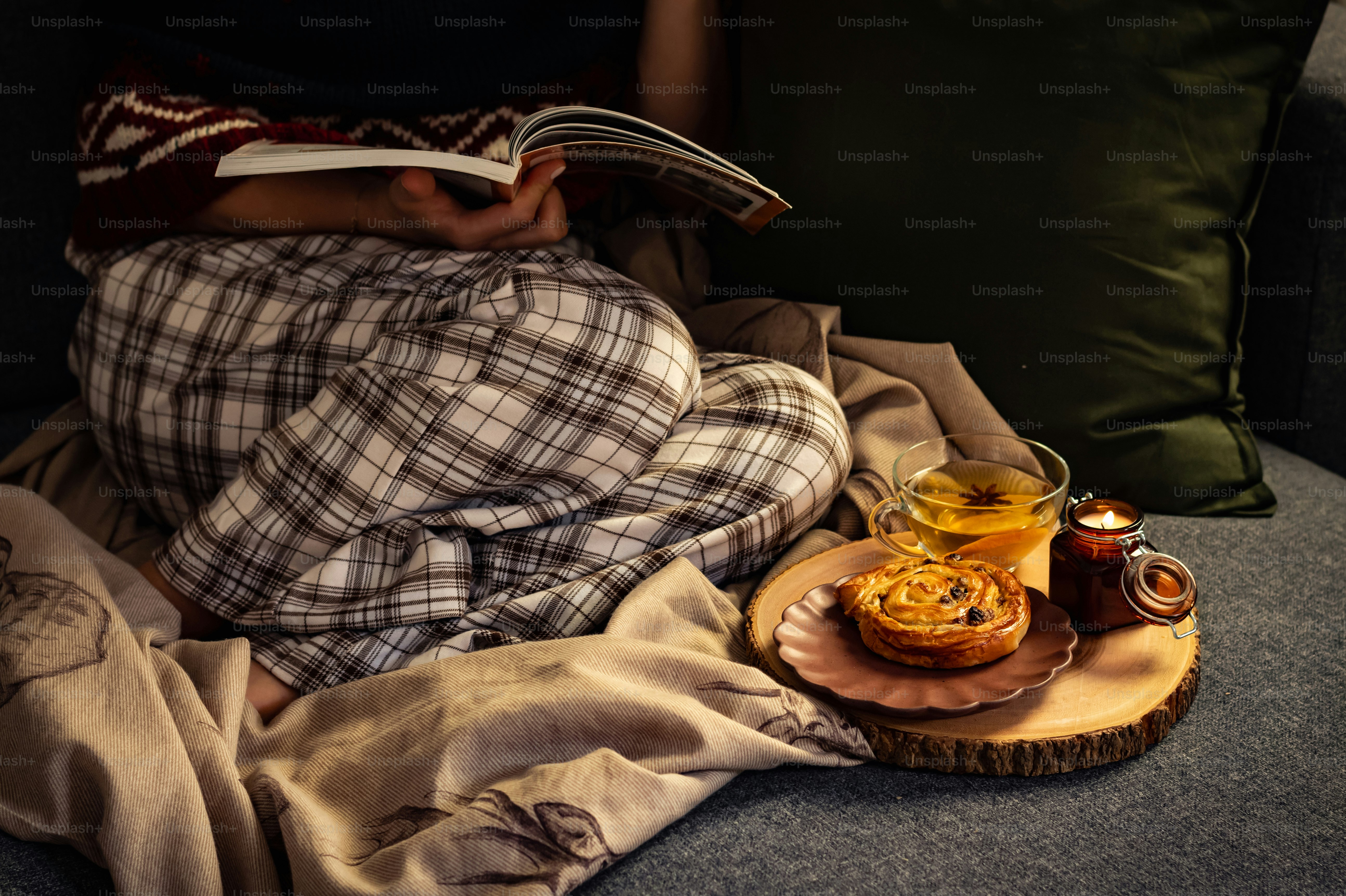 una persona sdraiata su un divano che legge un libro