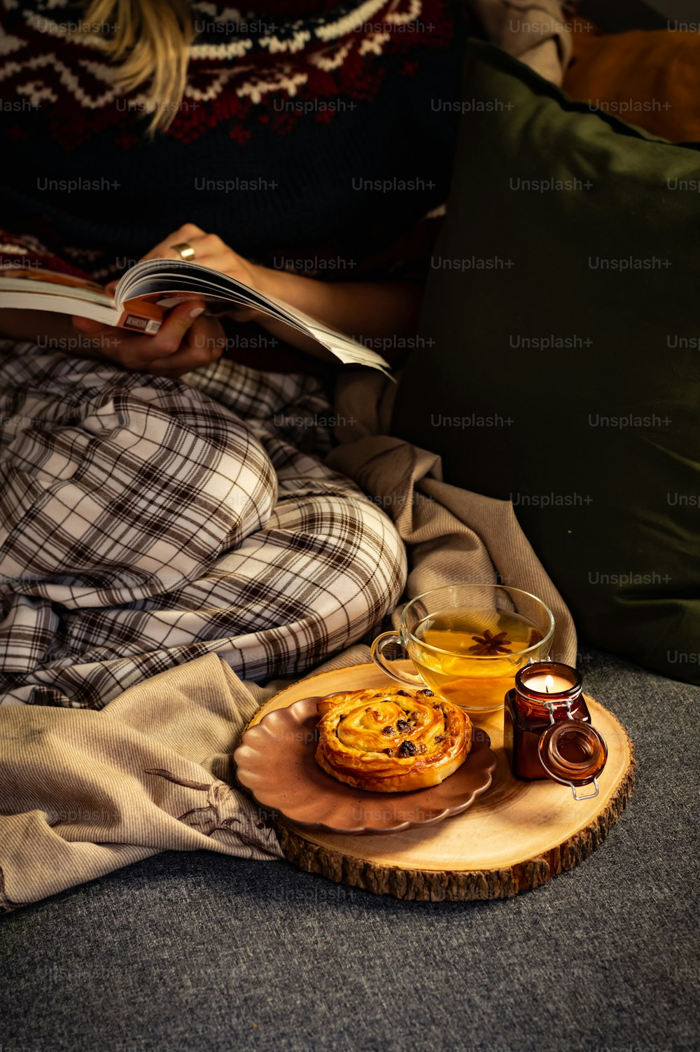 Una persona sentada en un sofá con un plato de comida y una taza de té