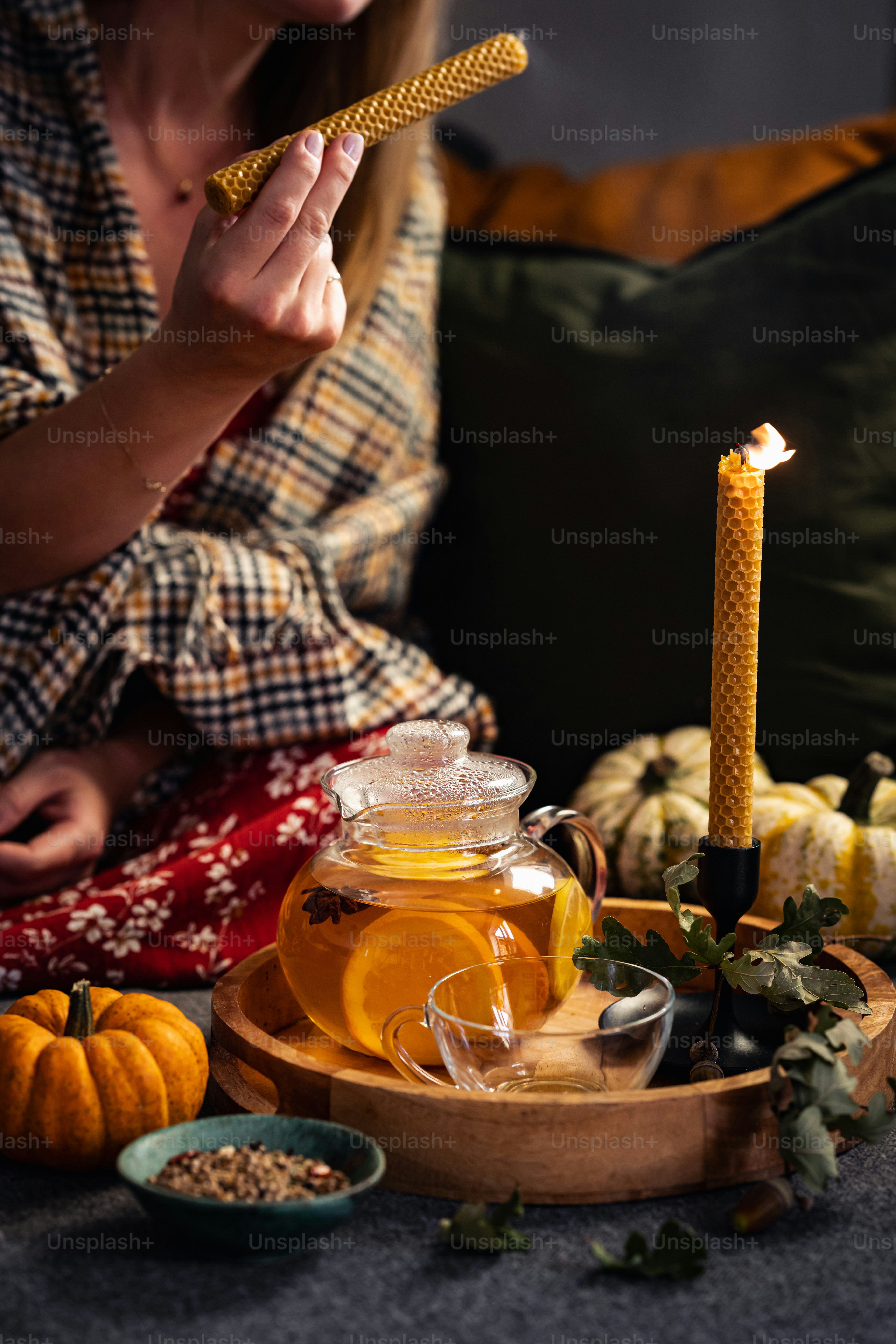 a woman sitting on a couch with a tea pot and a candle