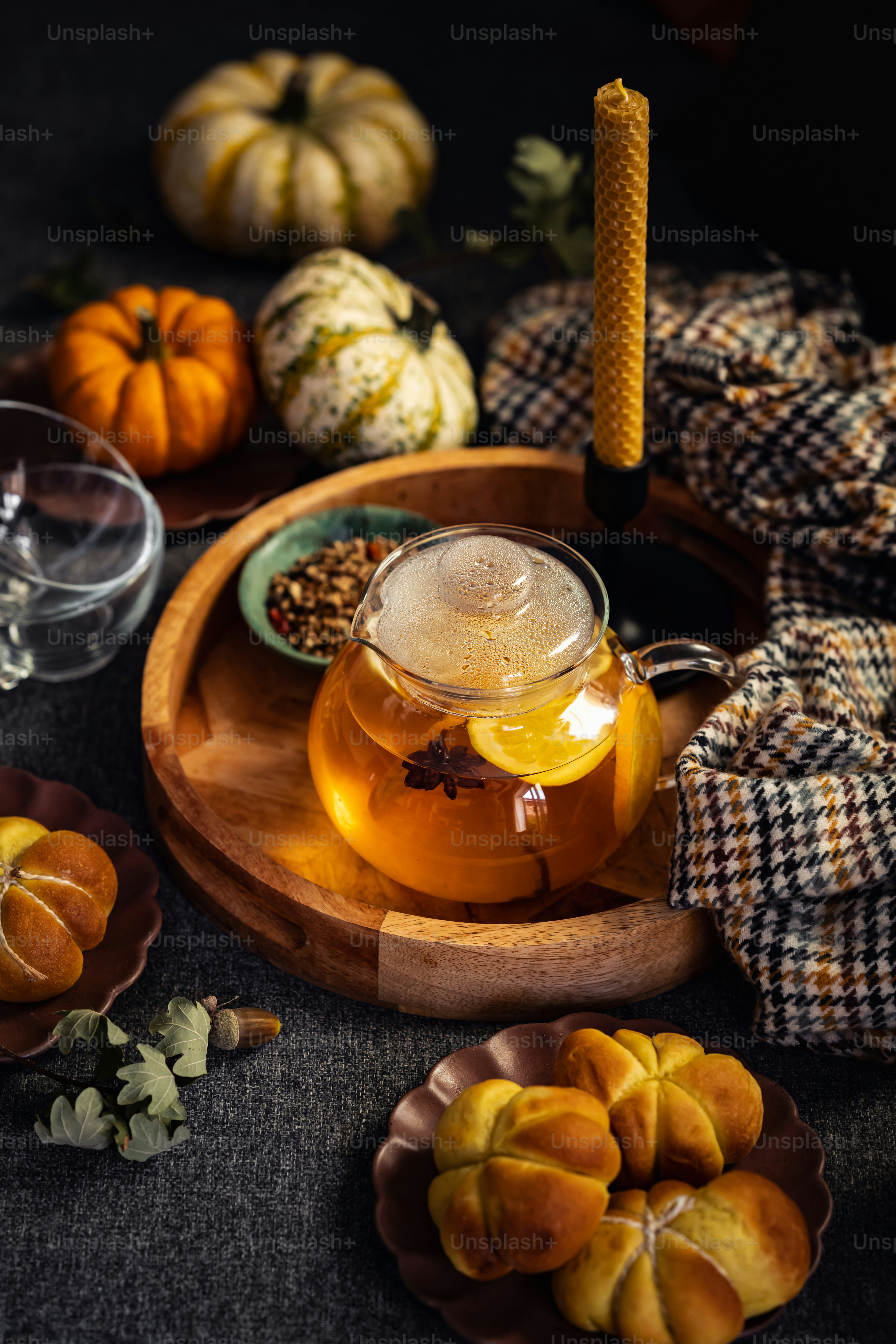 a glass tea pot filled with liquid next to a plate of pumpkins