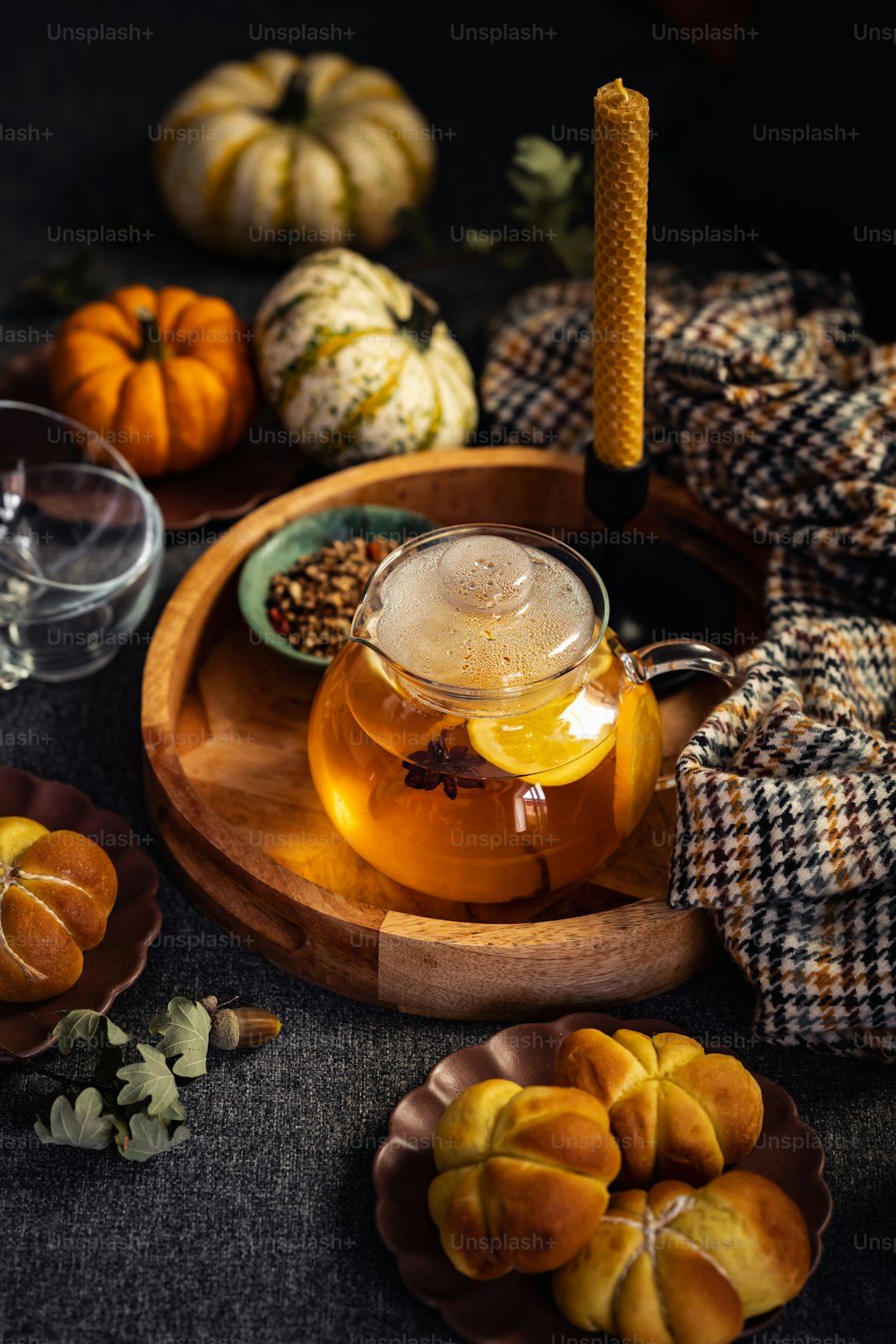 a glass tea pot filled with liquid next to a plate of pumpkins