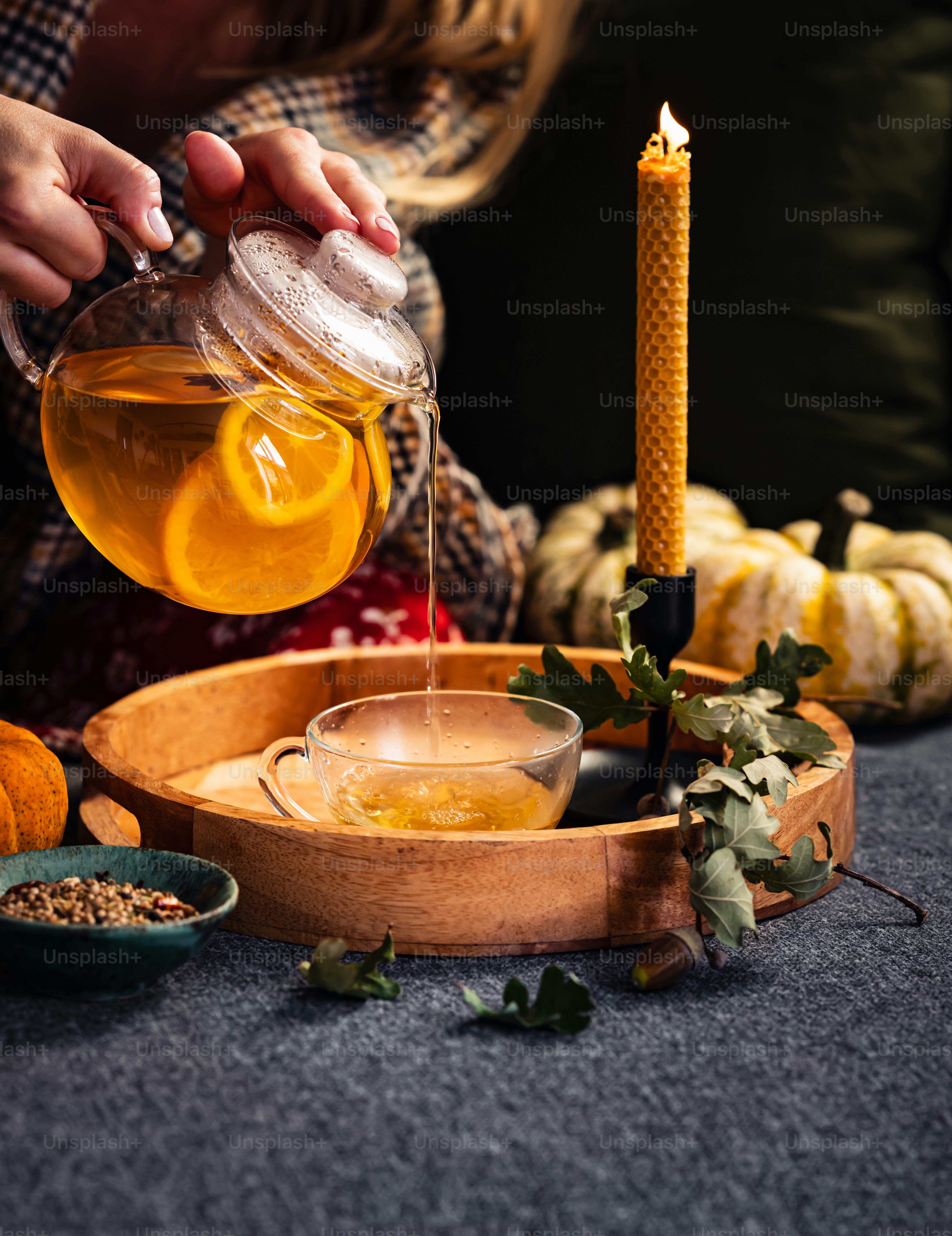 a woman pouring tea into a glass cup