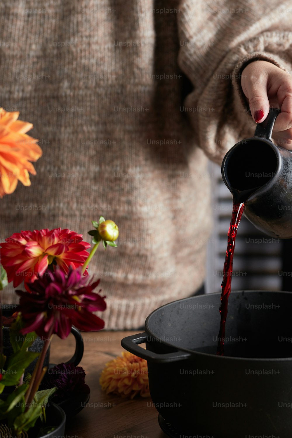 a woman pours red wine into a pot
